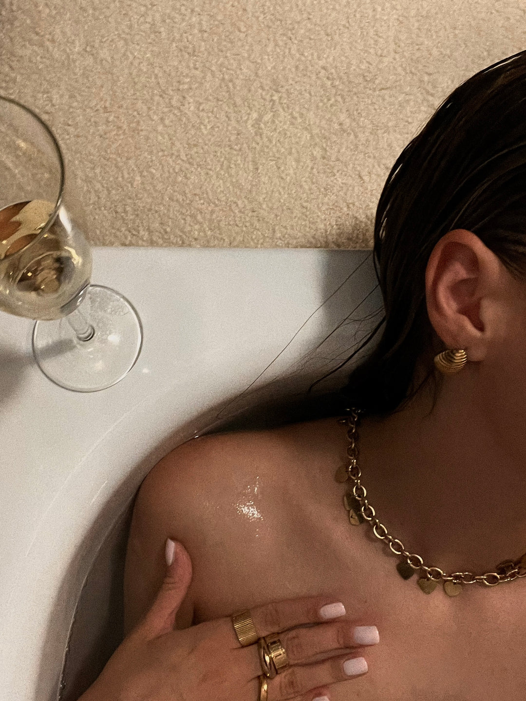 Model in der Badewanne, trägt "Endless Love" Halskette und "Organic Drop" Creole, kombiniert mit Ringen